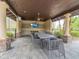 Covered outdoor dining area with a large table, chairs, and mounted TV at 28923 Lucero Ln, Wesley Chapel, FL 33543