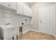 Functional laundry room with utility sink, overhead cabinets, and tile flooring at 5073 Stone Harbor Cir, Wimauma, FL 33598