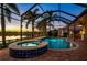 Screened-in pool and spa area overlooking serene lake with palm trees at 5073 Stone Harbor Cir, Wimauma, FL 33598