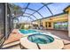 Enclosed pool and hot tub area with brick patio and outdoor kitchen, perfect for relaxation at 5073 Stone Harbor Cir, Wimauma, FL 33598