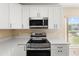 Close-up of updated kitchen with stainless steel microwave and range, quartz countertops, and white cabinetry at 5105 Gato Del Sol Cir, Wesley Chapel, FL 33544
