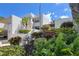 Beautiful exterior view of a white condo building with tropical landscaping and a sunny sky at 523 Bayport Way # 523, Longboat Key, FL 34228