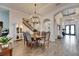 Elegant dining room with a decorative chandelier, wood-look tile flooring, and seamless access to the stairway and main entrance at 5402 Limelight Dr, Apollo Beach, FL 33572