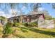 Charming single-Gathering home features a manicured lawn, a gray exterior, and red trim on the window and roof at 5741 Riddle Rd, Holiday, FL 34690