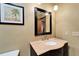 Bathroom vanity with beige marble counter, dark cabinets, dark framed mirror and palm tree art at 6614 Blackfin Way, Apollo Beach, FL 33572