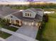 Stunning two-story home with a three-car garage, manicured lawn and a pond view at sunset at 7415 Paradiso Dr, Apollo Beach, FL 33572
