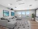 Bright living room features gray sectional, geometric rug, beach art, and abundant natural light at 7415 Paradiso Dr, Apollo Beach, FL 33572