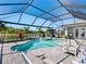 Screened-in pool with spa overlooking backyard lake, outdoor seating, and lush tropical landscaping at 7415 Paradiso Dr, Apollo Beach, FL 33572
