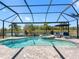 Screened in pool with spa overlooking backyard lake, lounge chairs, and lush tropical landscaping at 7415 Paradiso Dr, Apollo Beach, FL 33572