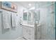 Well-lit bathroom featuring a glass shower, white vanity with modern fixtures, and stylish decorative art at 7932 Sailboat Key S Blvd # 806, South Pasadena, FL 33707
