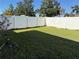 Fenced in back yard with green grass and bright white vinyl fence with trees behind it at 9613 Jasmine Brook Crk, Land O Lakes, FL 34638
