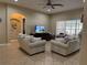 Spacious living room featuring tile floors, two striped couches, a ceiling fan, and a TV at 9613 Jasmine Brook Crk, Land O Lakes, FL 34638