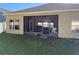 Enclosed patio with tan exterior and a variety of patio furniture, grill, and view of the green yard at 9613 Jasmine Brook Crk, Land O Lakes, FL 34638