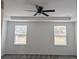 Bright bedroom featuring a tray ceiling, fan, and two windows at 10240 Meadow Wren Ave, Weeki Wachee, FL 34613