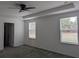 Bright bedroom featuring a tray ceiling, fan, and two windows at 10240 Meadow Wren Ave, Weeki Wachee, FL 34613