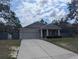 Well-maintained single-Gathering home with a spacious driveway, gray facade, and appealing front garden at 10240 Meadow Wren Ave, Weeki Wachee, FL 34613