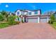 Traditional two-story home featuring a three-car garage, brick driveway, and meticulous landscaping at 11086 Sundrift Dr, Tampa, FL 33647