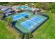 Aerial view of tennis courts and community pool area surrounded by lush green landscaping and tropical palm trees at 11086 Sundrift Dr, Tampa, FL 33647