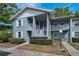 Two-story condo with a gray exterior, white railings, and a small garden area at 1438 Millstream Ln # 201, Dunedin, FL 34698