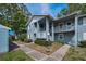 Two-story condo exterior showcasing the gray facade, white railing balconies, and well-maintained landscaping at 1438 Millstream Ln # 201, Dunedin, FL 34698