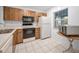 Bright kitchen with wood cabinets, white appliances, and tile flooring at 1438 Millstream Ln # 201, Dunedin, FL 34698
