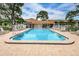 Community pool featuring plenty of deck chairs and shady trees at 1438 Millstream Ln # 201, Dunedin, FL 34698