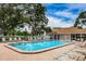 Community pool with plenty of lounge chairs and well-maintained fencing at 1438 Millstream Ln # 201, Dunedin, FL 34698