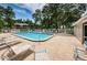Community pool with lounge chairs on a sunny day at 1438 Millstream Ln # 201, Dunedin, FL 34698