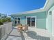 Outdoor deck area with table and seating. The turquoise-colored house is surrounded by palm trees at 16109 3Rd E St, Redington Beach, FL 33708
