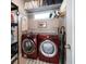 Functional laundry room with red Samsung washer and dryer, shelving, and storage space at 16109 3Rd E St, Redington Beach, FL 33708