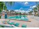An inviting community pool and lounge area under a bright blue sky is surrounded by tropical landscaping and is perfect for relaxation at 18399 Gulf Blvd # 389, Indian Shores, FL 33785