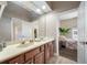 Well-lit bathroom with double sinks, a spacious vanity, and an open doorway to the bedroom at 19005 Cour Ests, Lutz, FL 33558