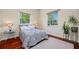 Cozy bedroom featuring wood floors, a patterned bedspread, and plenty of natural light through two windows at 19005 Cour Ests, Lutz, FL 33558