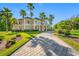 Stunning exterior view of luxury home with lush landscaping, brick driveway and towering palm trees at 19005 Cour Ests, Lutz, FL 33558