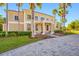 Impressive front exterior with a brick driveway, manicured lawn and mature palm trees at 19005 Cour Ests, Lutz, FL 33558