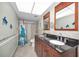 Bathroom featuring a double sink vanity, mirror, shower, and commode at 200 Glennes Ln # 201, Dunedin, FL 34698