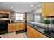 The kitchen has wooden cabinets, black appliances, granite countertops and a view into the living area at 200 Glennes Ln # 201, Dunedin, FL 34698