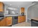 Kitchen with wooden cabinets, black appliances, and an open view to the living area through an arched opening at 200 Glennes Ln # 201, Dunedin, FL 34698