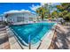 Community pool with cool, clear water, surrounded by a red brick tile patio and lounge chairs at 200 Glennes Ln # 201, Dunedin, FL 34698