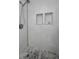Close-up shot of shower with a shower head, drain, marble tile and two built-in shelves at 200 Glennes Ln # 201, Dunedin, FL 34698