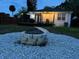 Backyard featuring stone fire pit, a walkway, patio, and manicured lawn, ideal for outdoor activities at 205 N Westland Ave, Tampa, FL 33606