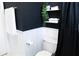 Modern bathroom with black walls, white wainscoting, a toilet, and a shower curtain at 205 N Westland Ave, Tampa, FL 33606