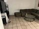 Living room with tile floors, dark couch, glass coffee table, and TV at 2610 E 26Th Ave, Tampa, FL 33605