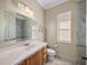 Bright bathroom featuring a vanity with marble countertop, toilet, window, and tiled shower with glass doors at 34201 Kentucky Derby Pl, Dade City, FL 33525