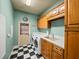 A laundry room with wood cabinets, black and white tiled flooring, and a front load washer and dryer at 34201 Kentucky Derby Pl, Dade City, FL 33525