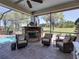 Cozy outdoor space with brick pavers, in-ground pool, manicured lawn and stone fireplace at 34201 Kentucky Derby Pl, Dade City, FL 33525