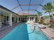 Enclosed pool area with a spa, lush tropical landscaping, brick pavers, and a view of the exterior living space at 34201 Kentucky Derby Pl, Dade City, FL 33525