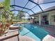 Enclosed pool area with a spa, lush landscaping, brick pavers, and a view of the outdoor kitchen area at 34201 Kentucky Derby Pl, Dade City, FL 33525