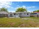 Wide shot of the backyard featuring grass, a patio and the back of the house with neutral paint at 5261 43Rd N Ave, St Petersburg, FL 33709