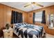 Cozy bedroom with wood paneled walls, ceiling fan and nice quilt at 5306 Mary St, Zephyrhills, FL 33542